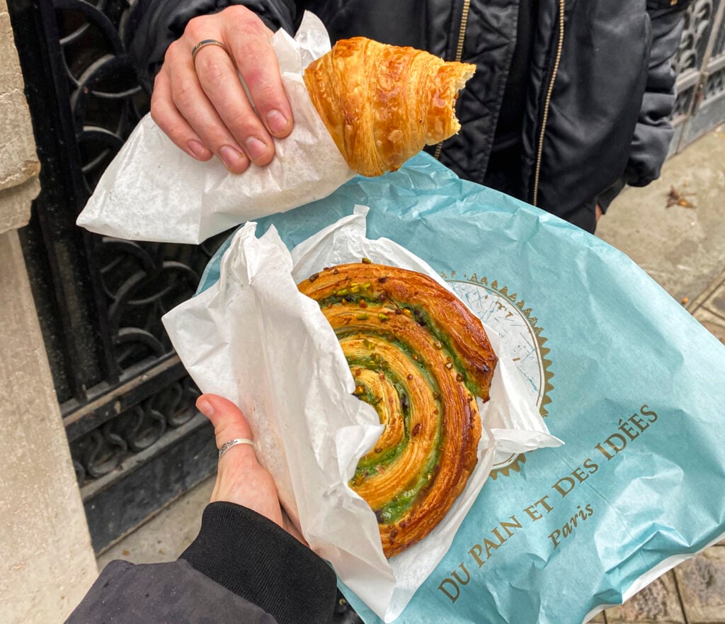 a croissant and a pistachio and chocolate swirl pastry in paris
