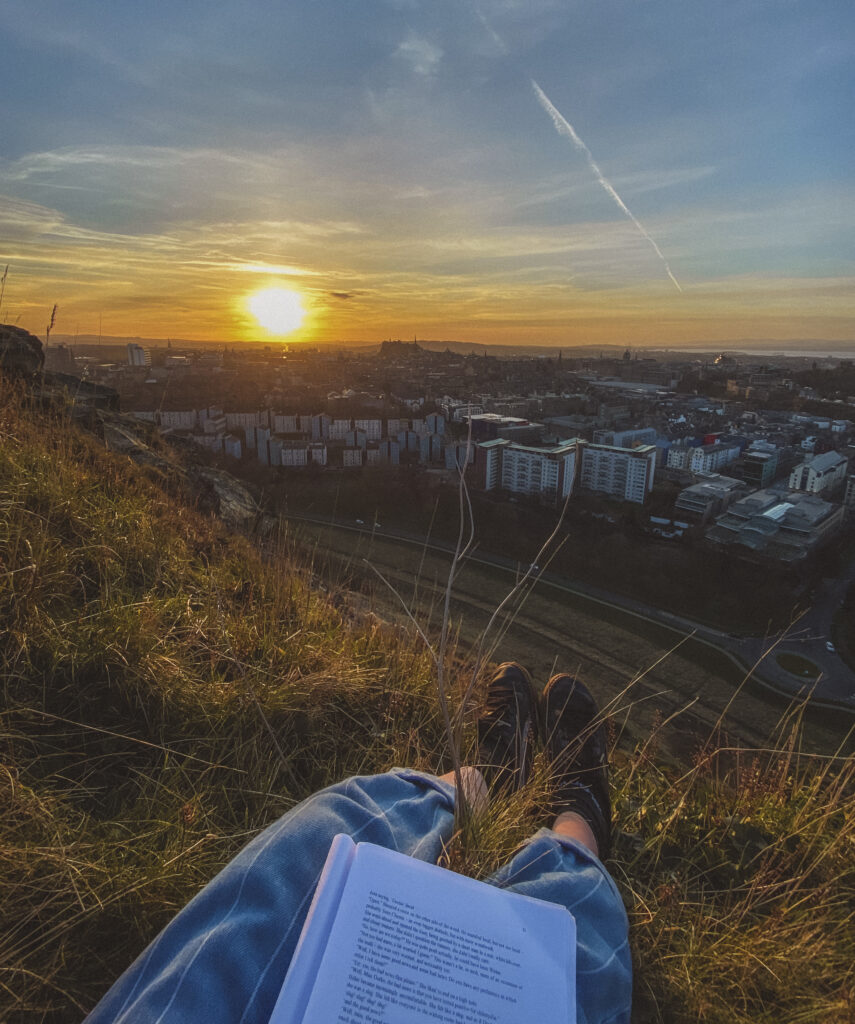 reading at sunset on arthurs seat in edinburgh
