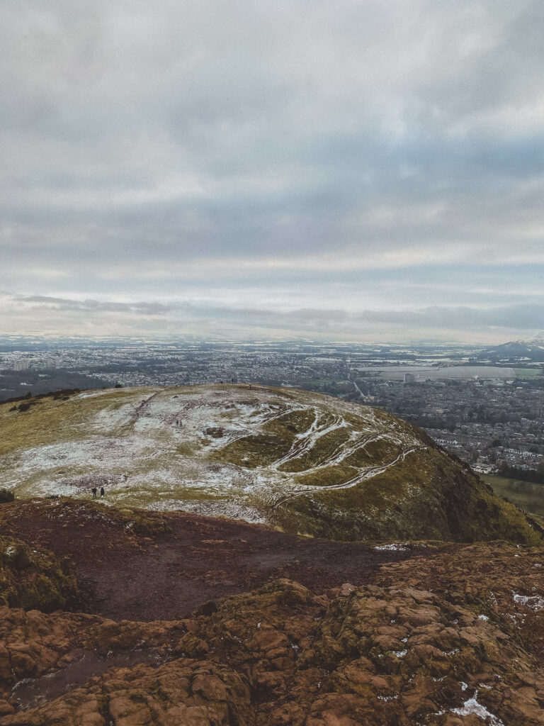 view from the top of arthurs seat in edinburgh on a cloudy day with frost on the hill